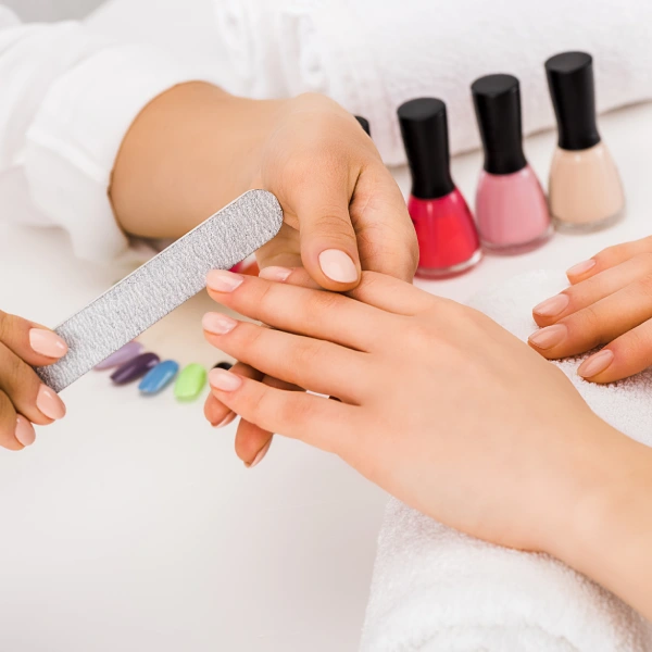 Cropped view of woman holding hand on towel while manicurist doing nail form